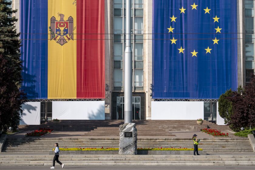 A woman runs past the government building, decorated with European Union and Moldovan flags in Chisinau, Moldova, Wednesday, May 31, 2023. Moldova will host the Meeting of the European Political Community on June 1, 2023. Preparations for a major summit of European leaders were still underway in Moldova on Wednesday, a sign of the Eastern European country’s ambitions to draw closer to the West and break with its Russian-dominated past amid the war in neighboring Ukraine. (AP Photo/Vadim Ghirda)