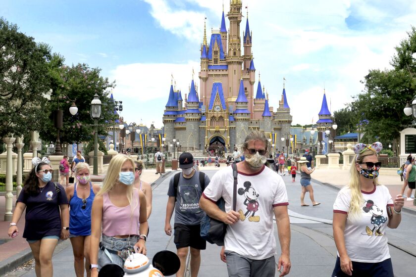 Guests wear masks as required to attend the official reopening day of the Magic Kingdom at Walt Disney World in Lake Buena Vista, Fla., Saturday, July 11, 2020. Disney reopened two Florida parks, the Magic Kingdom and Animal Kingdom, Saturday, with limited capacity and safety protocols in place in response to the coronavirus pandemic. (Joe Burbank/Orlando Sentinel via AP)