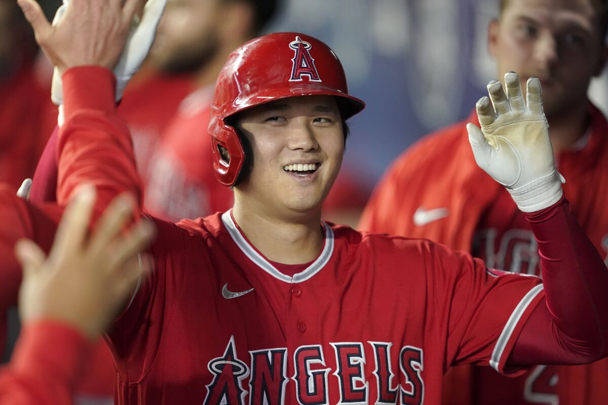 The Angels' Shohei Ohtani smiles and gets high-fives from teammates