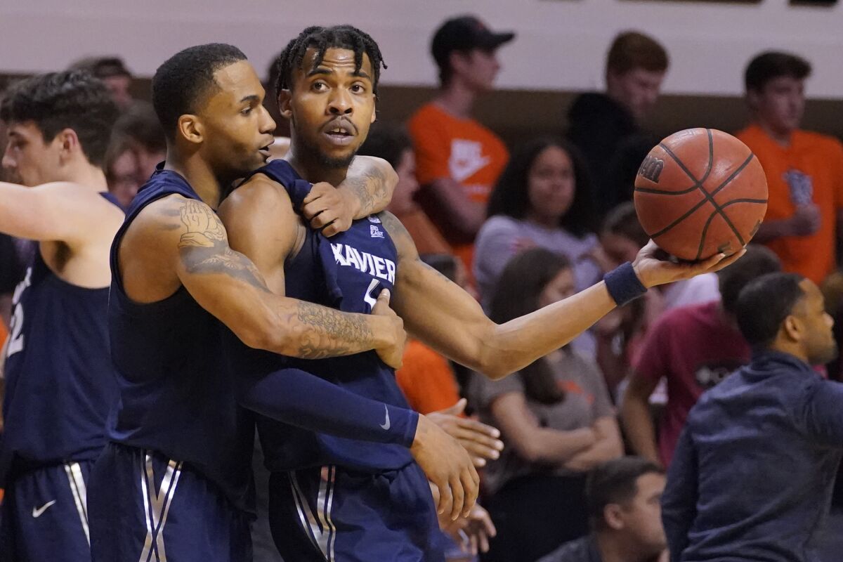 Xavier guard Dwon Odom, left, celebrates with teammate Paul Scruggs, right, after Xavier defeated Oklahoma State in an NCAA college basketball game Sunday, Dec. 5, 2021, in Stillwater, Okla. (AP Photo/Sue Ogrocki)