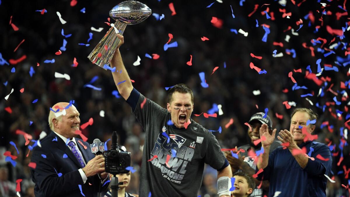 Flanked by Fox Sports broadcaster Terry Bradshaw, left, and New England coach Bill Belichick, Patriots quarterback Tom Brady holds the Vince Lombardi Trophy after a 34-28 overtime victory over the Atlanta Falcons in Super Bowl LI.