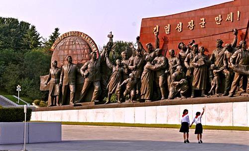 Schoolgirls hold hands as they walk past the Mansudae Grand Monument, a sculpture representing North Korea's struggle against Japanese imperialism.
