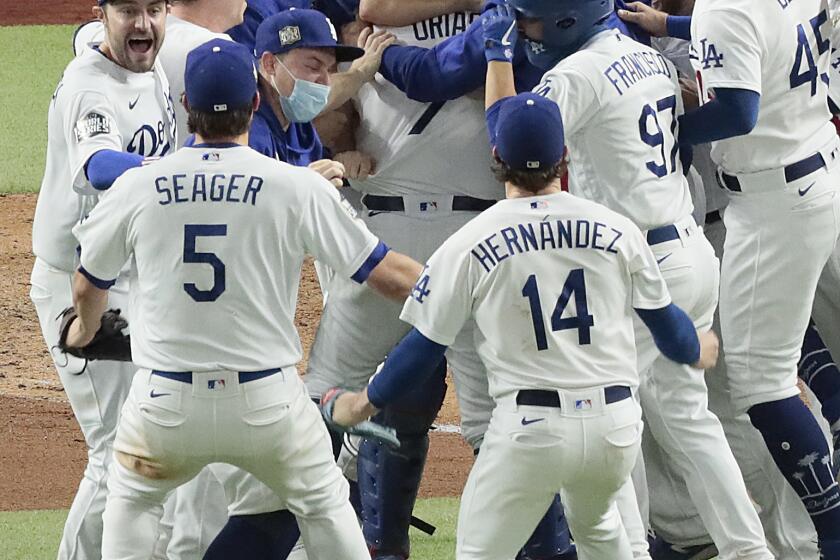 Arlington, Texas, Tuesday, October 27, 2020 Los Angeles Dodgers starting pitcher Julio Urias (7) is mobbed by teammates after closing to a 3-1 win over the Rays to clinch the World Series at Globe Life Field. (Robert Gauthier/ Los Angeles Times)