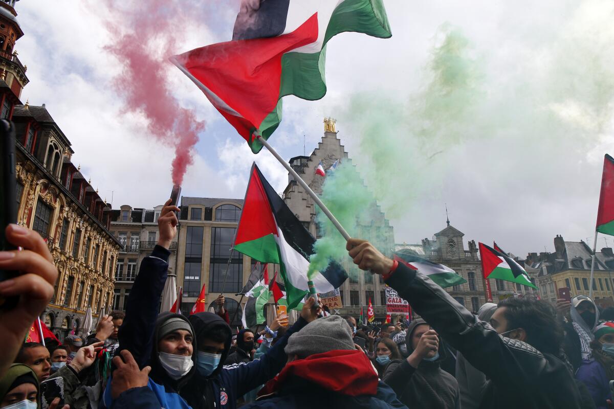 Unas personas sostienen banderas palestinas y bengalas 