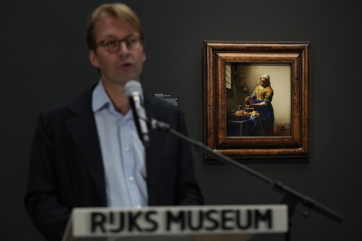 Man speaking with Vermeer's 'The Milkmaid' in the background