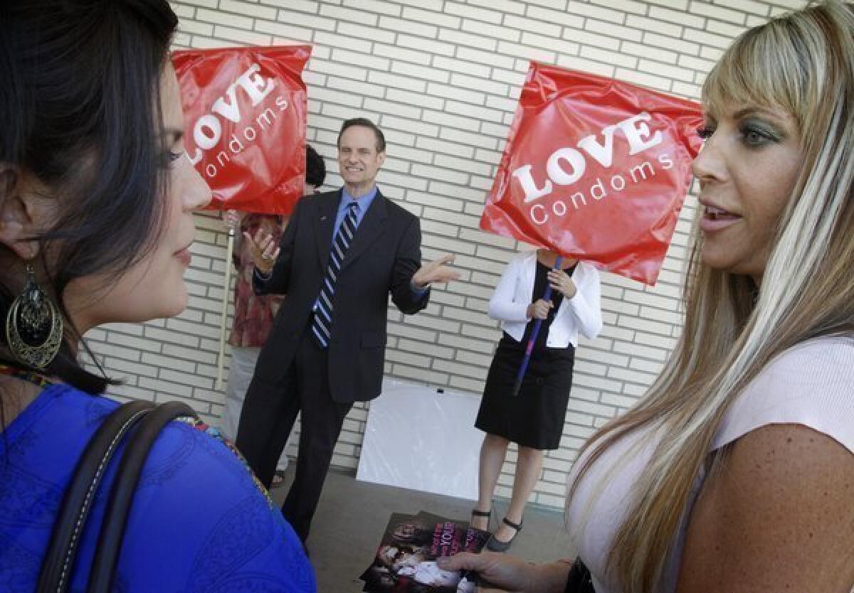 Former adult film industry performers Madelyne Hernandez, left, and Shelley Lubben chat as Michael Weinstein, AIDS Healthcare Foundation president, addresses a small crowd in 2010 about mandating that pornography actors use condoms.