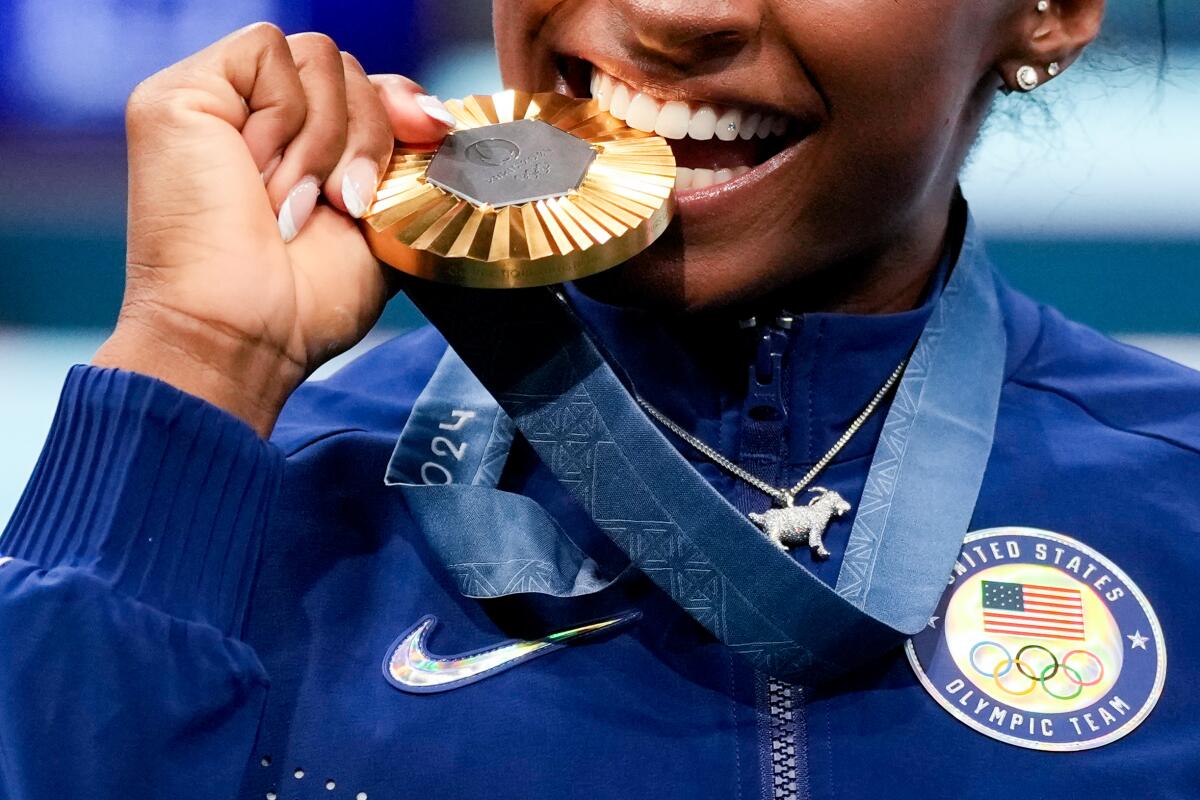 Simone Biles with a goat necklace and gold medal after winning thee women's gymnastics all-around final.