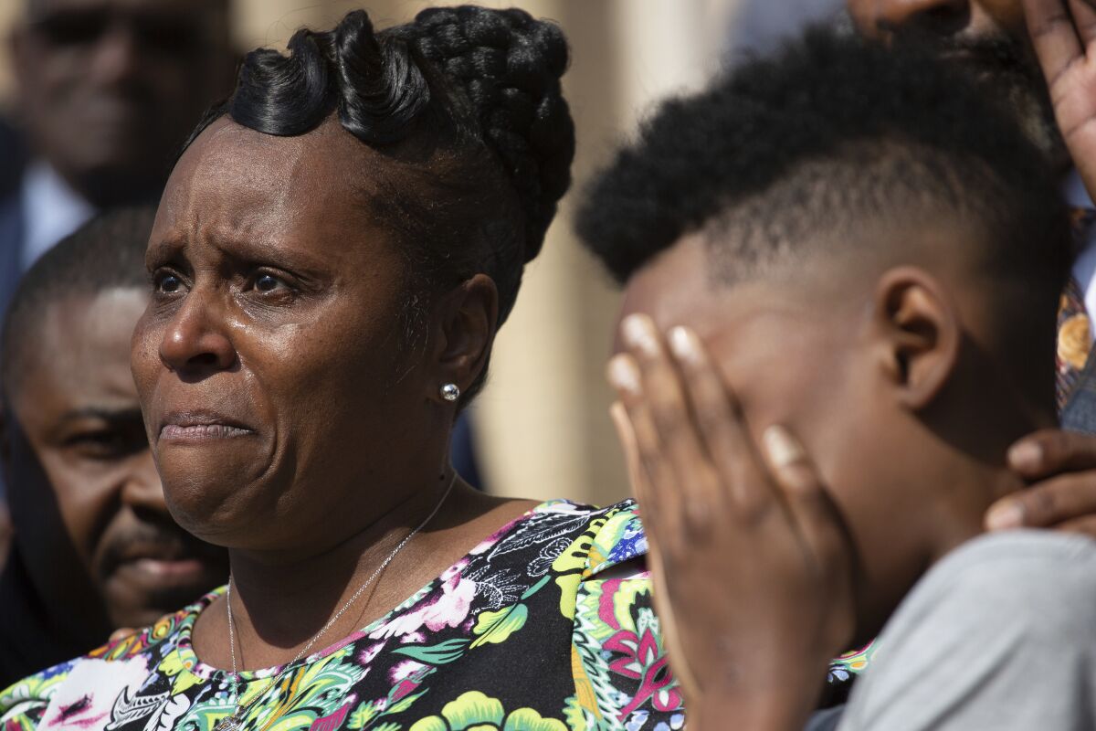 RETRANMISSION TO CORRECT NAME TO JAQUES “JAKE” PATTERSON - Tirzah Patterson, former wife of Buffalo shooting victim Heyward Patterson, speaks as her son, Jaques "Jake" Patterson, 12, covers his face during a press conference outside the Antioch Baptist Church on Thursday, May 19, 2022, in Buffalo, N.Y. (AP Photo/Joshua Bessex)