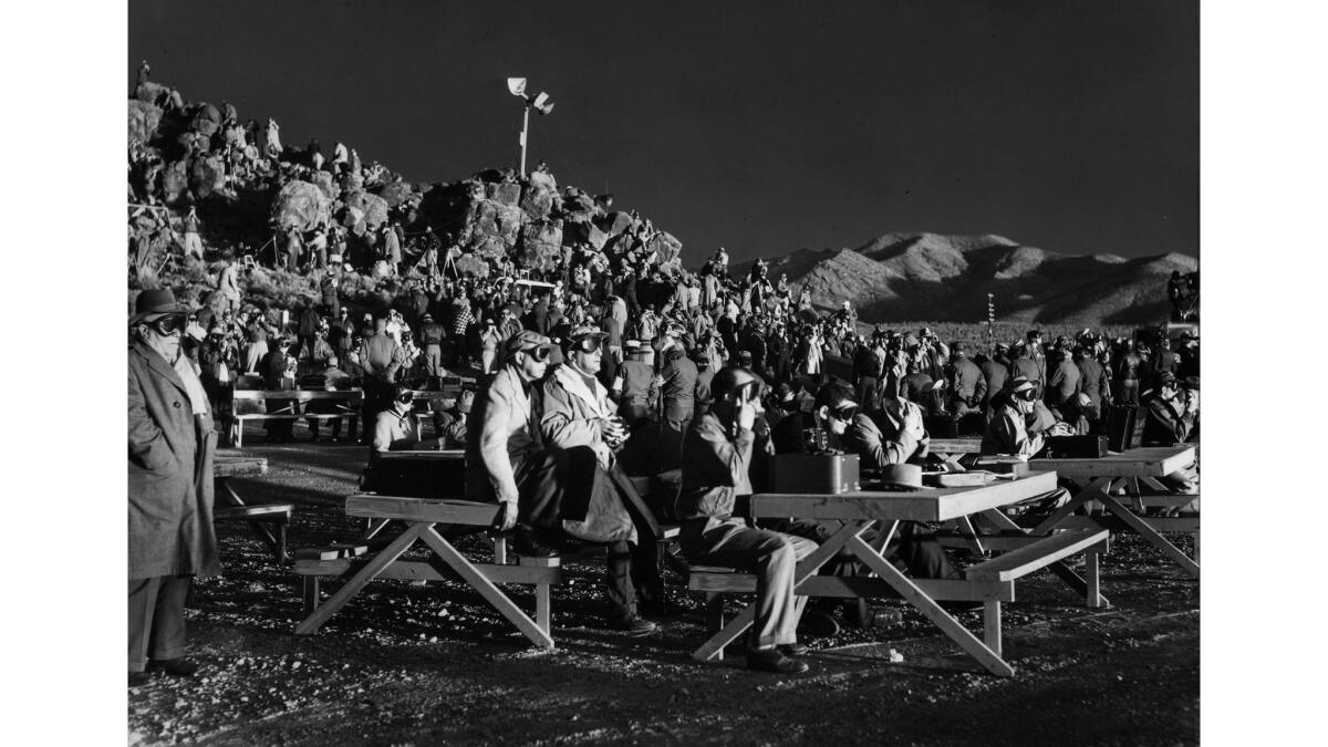 March 17, 1953: Journalists on News Nob, seven miles from the center of an atom bomb test, are lighted by the flare of the explosion. Those unequipped with protective glasses turn their backs, as directed via loudspeaker atop a rocky peak.