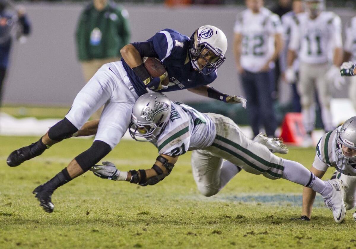 St. John Bosco's Shay Fields jumps over De La Salle's Dasmond Tautalatasi in the first half of a CIF Open Division high school football championship game in Carson on Dec. 21. Football is among the sports that put teen athletes at risk for head injury.