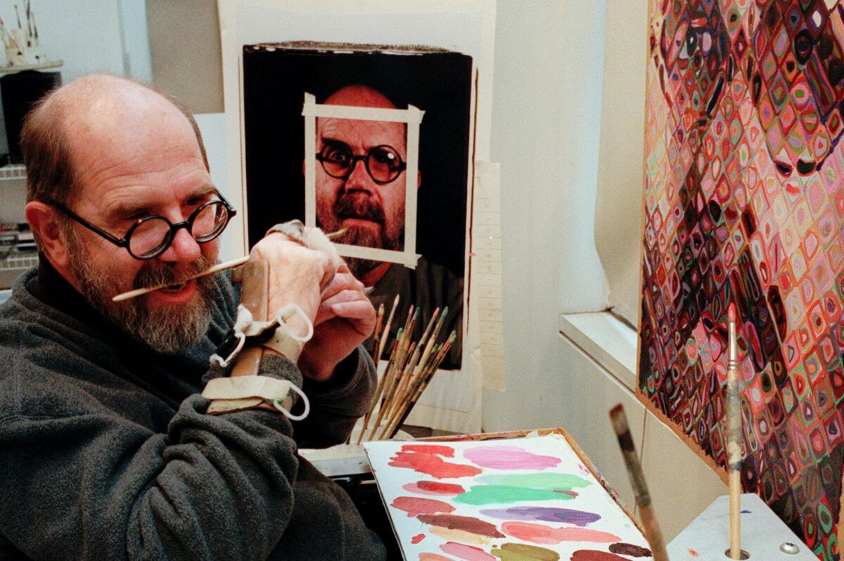 Chuck Close uses a hand brace to hold his paint brush