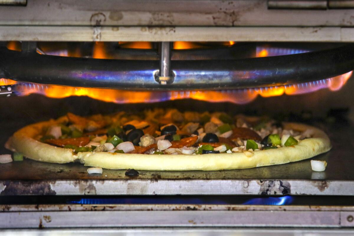 A pizza with toppings is cooked inside a deck oven