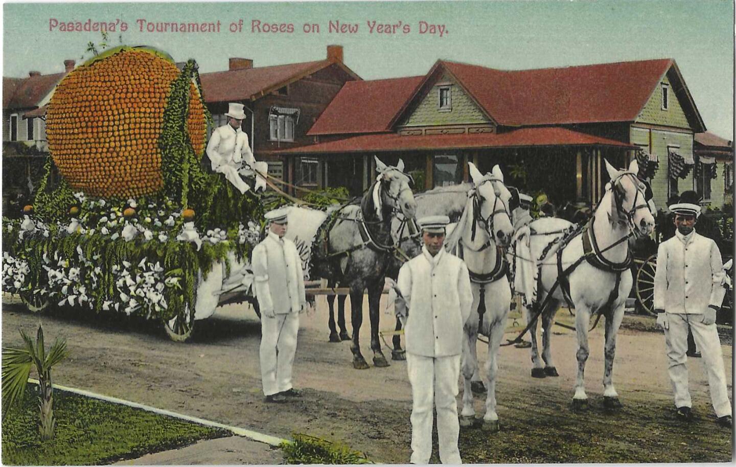 A large orange on a flower-decked float. Men in white uniforms stand near a small team of horses