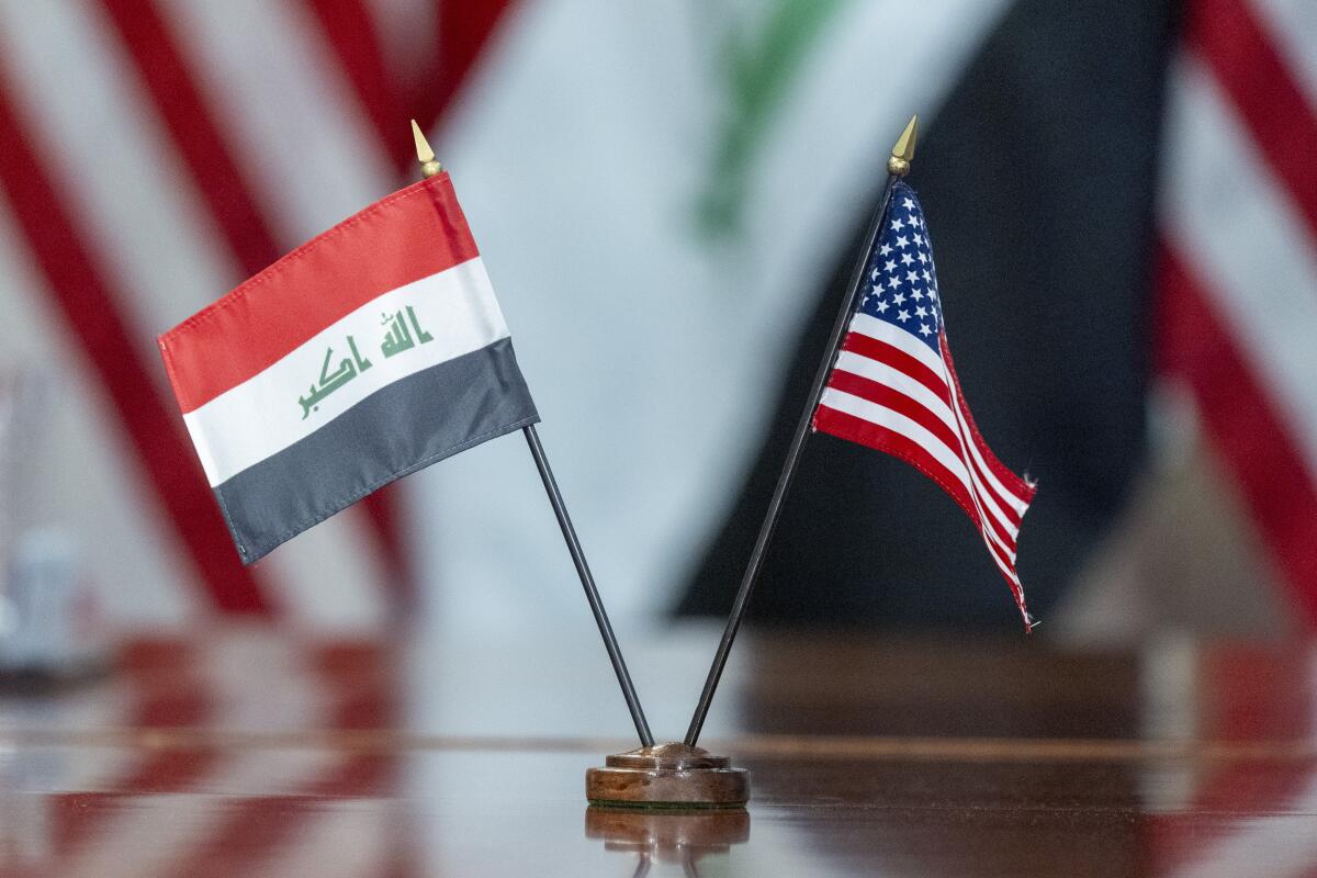 The flags of Iraq and the United States are placed on a table.