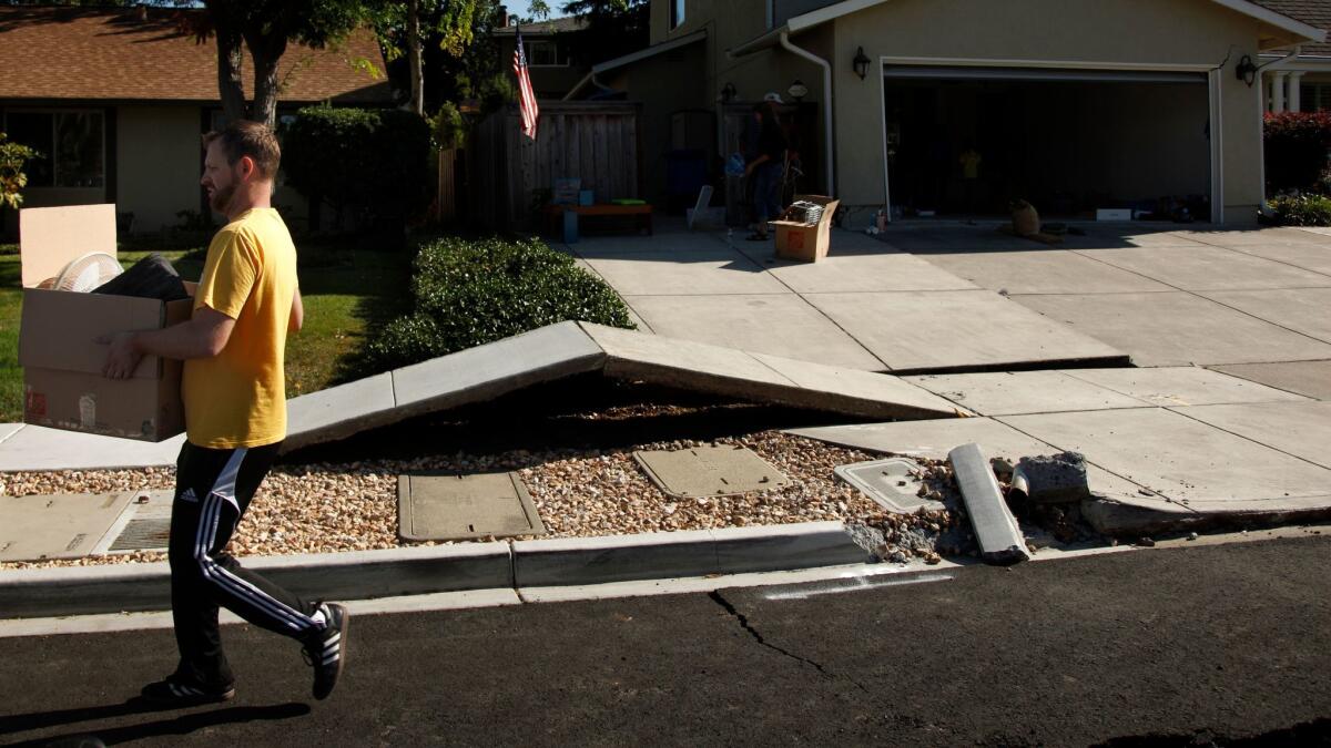 Scott Whitlock walks over a stretch of buckled sidewalk while helping his parents move out of their damaged home after the 2014 earthquake that struck the Napa area.