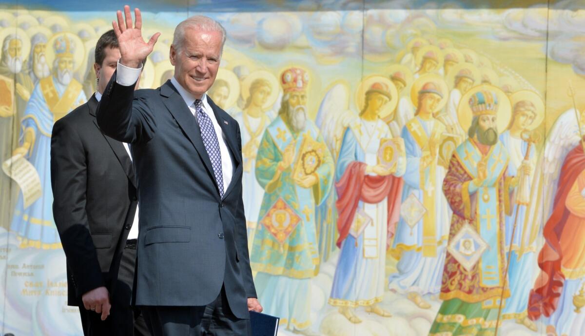 Joe Biden waves as he walks in front of Mykhaylo Gold Domes wall frescoes in Kyiv during a visit in 2014 while he was vice president.