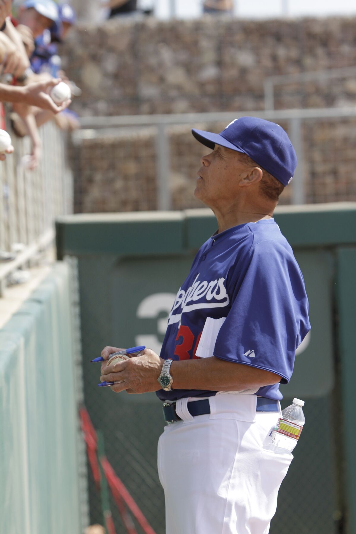 Maury Wills signs autographs before a Dodgers spring training baseball game against the Milwaukee Brewers