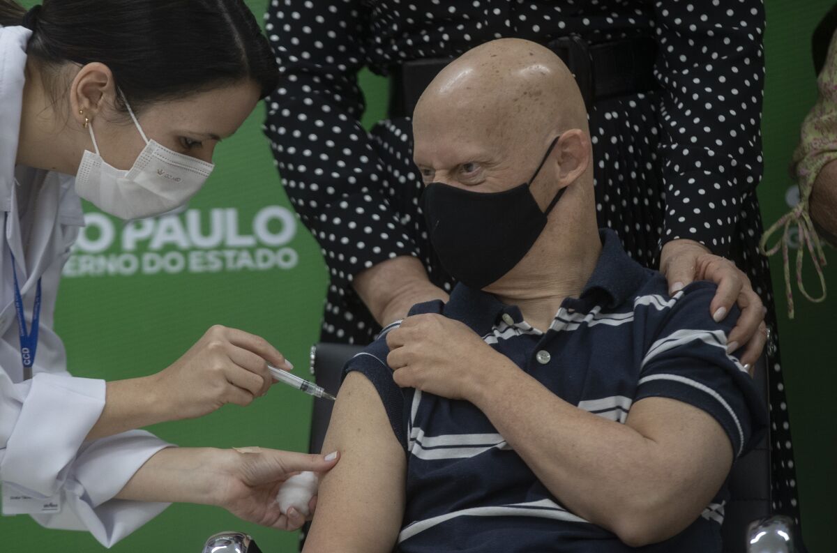A health worker gives a shot of the AstraZeneca COVID-19 vaccine to Sergio Quitanilla, 55, during a priority vaccination program for people with Down syndrome, in Sao Paulo, Brazil, Monday, May 10, 2021. (AP Photo/Andre Penner)