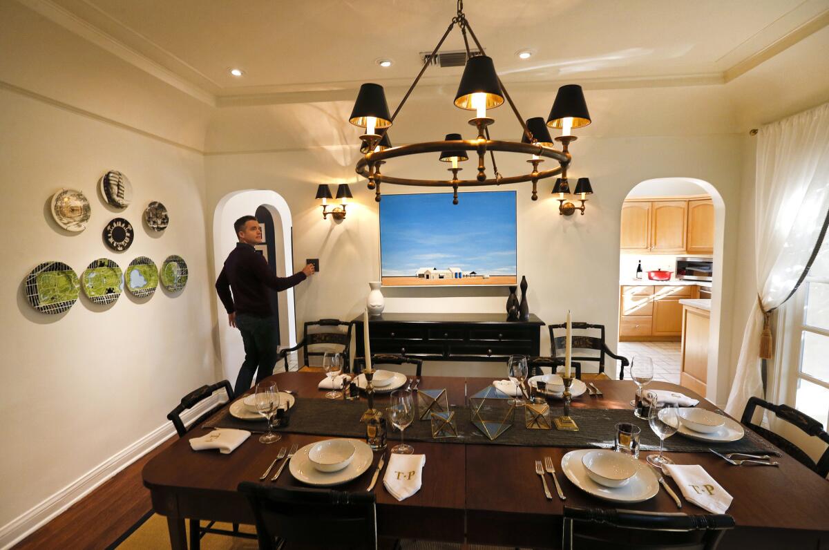 Patrick Wildnauer turns the lights on inside dining room. This is the original light fixture but the shades were changed from pleated white to black and gold. (Mel Melcon / Los Angeles Times)