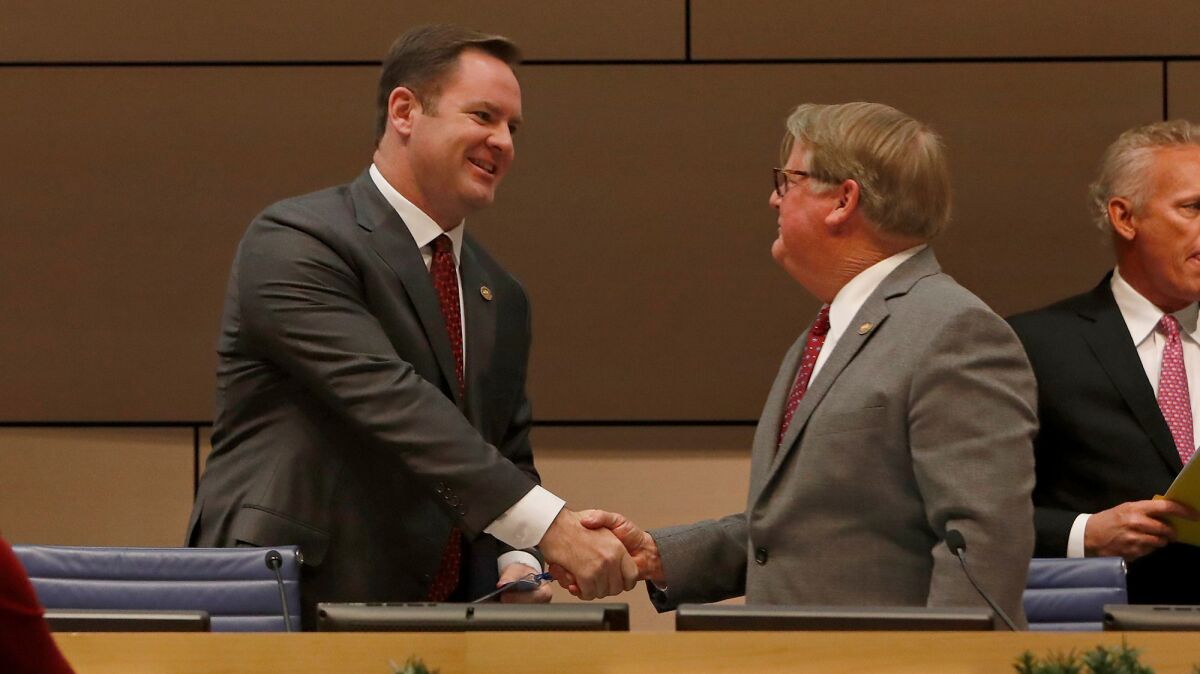 Will O'Neill, left, the new mayor pro tem of Newport Beach, and new Mayor Marshall "Duffy" Duffield shake hands as they take their seats on the City Council dais Tuesday night.