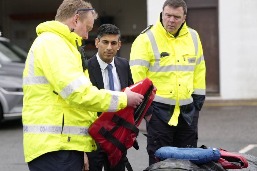 Britain's Prime Minister Rishi Sunak, second center, speaks with members of the Home Office contracted staff, while looking at a lifevest and rubber dinghy, during a visit to a Home Office joint control room in Dover, Kent, England, Tuesday, March 7, 2023. (AP Photo/Kirsty Wigglesworth, Pool)
