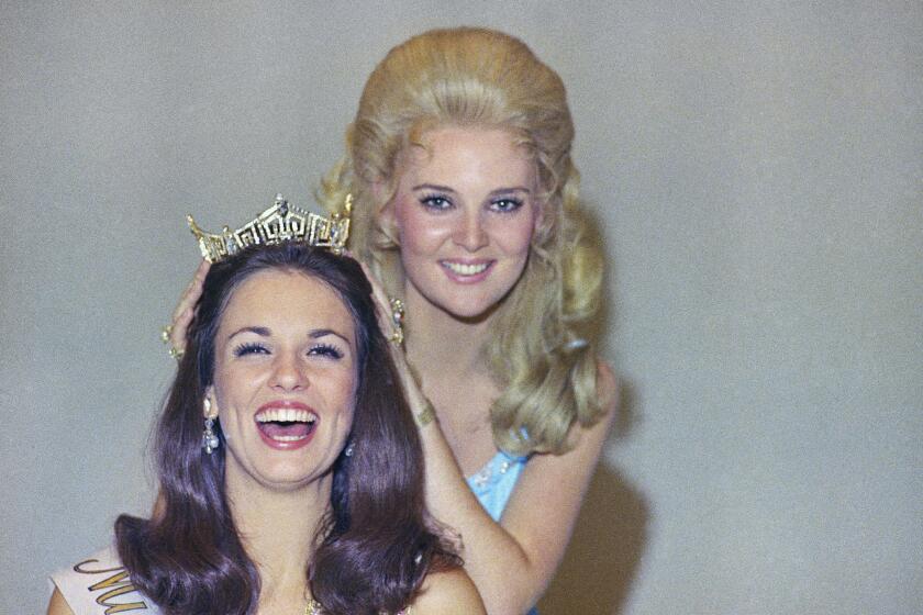 Phyllis George, the former Miss Texas won the national title of Miss America in Atlantic City on Sept. 12, 1970, having the crown placed on her head by the former Miss America, Pamela Anne Eldred of Michigan. (AP Photo)