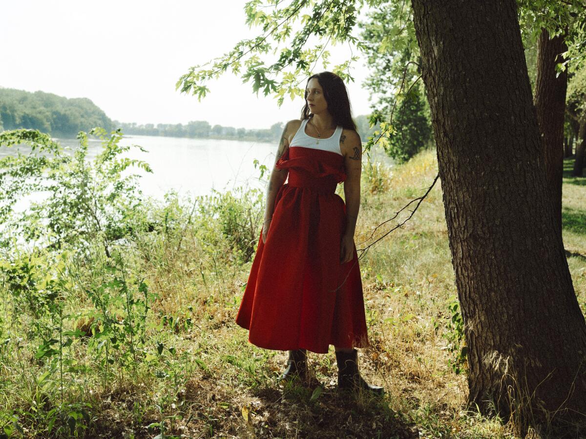 Woman in a red dress standing by a lake