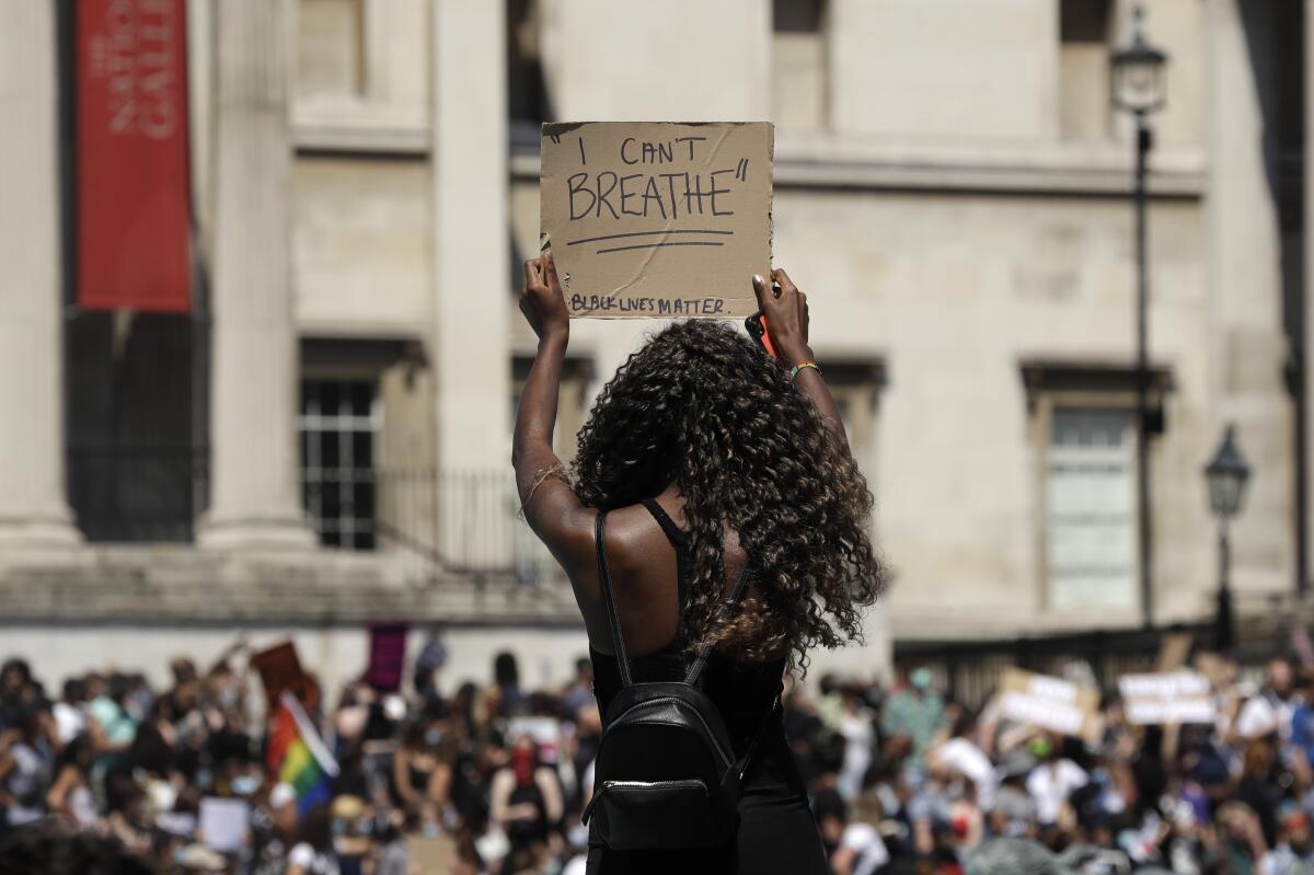 A woman holds up a sign as people gather in Trafalgar Square in London.