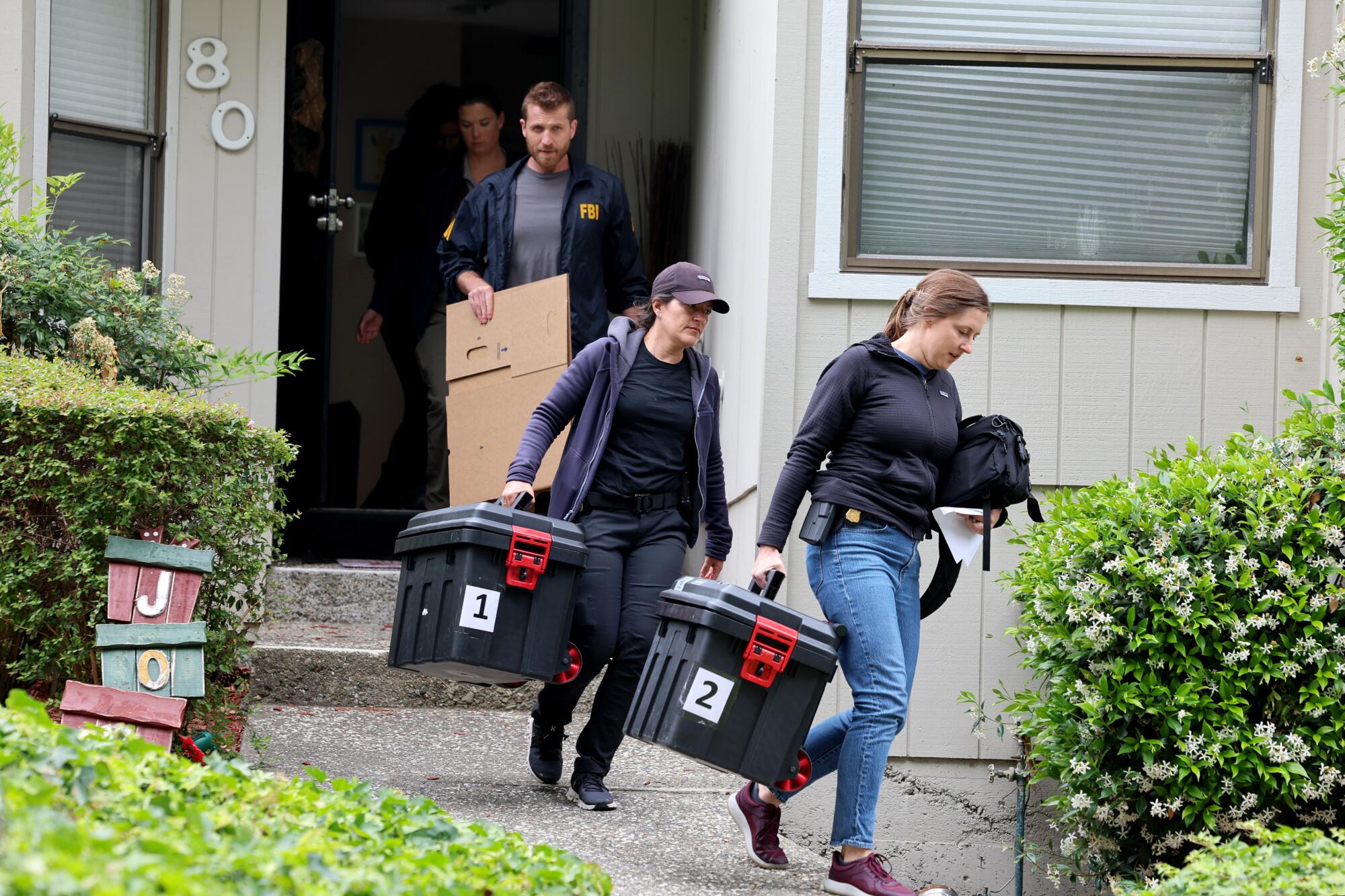 People carry storage bins from a home.