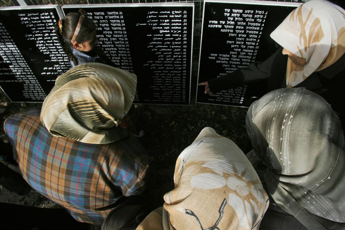 Palestinian relatives of residents of the Arab village of Deir Yassin stand over plaques listing names