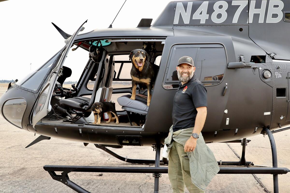 Pilot Trevor Skaggs standing by a helicopter with dogs inside