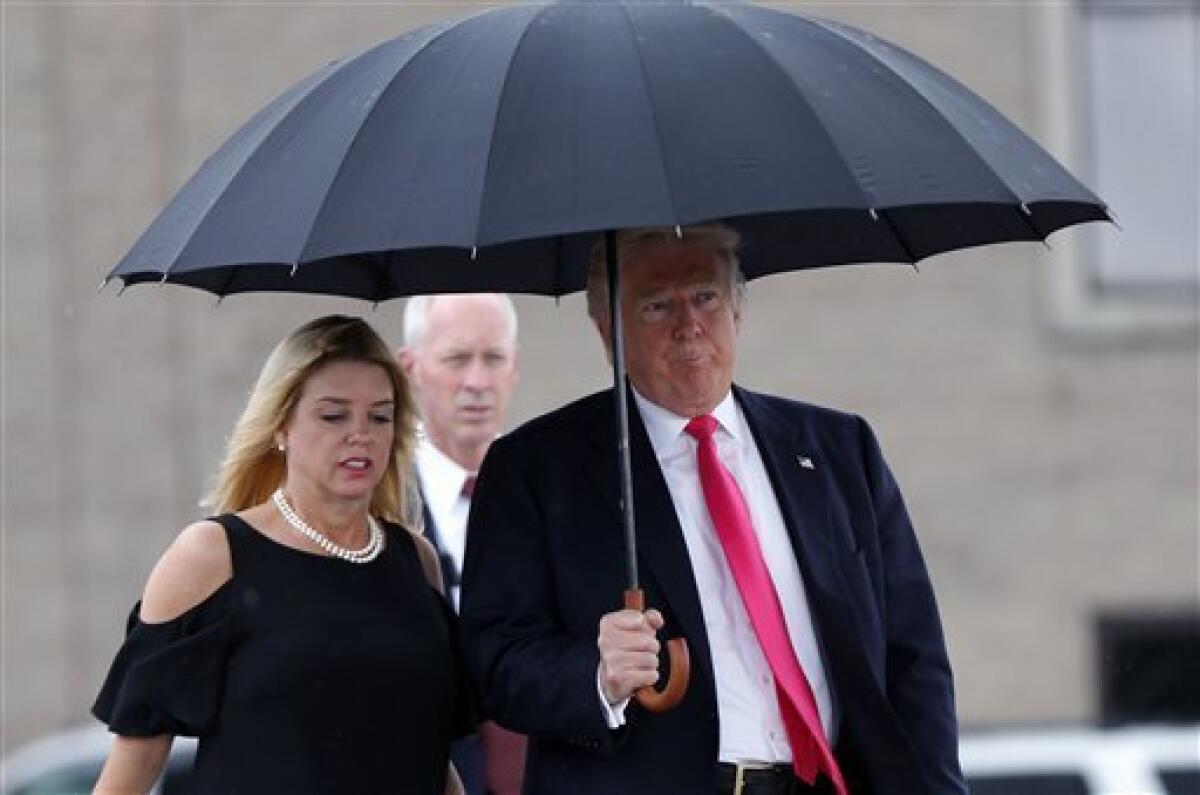 El candidato presidencial republicano Donald Trump camina bajo la lluvia junto con la secretaria de Justicia de Florida Pam Bondi hacia un acto de campaña en Tampa, el miércoles 24 de agosto del 2016.
