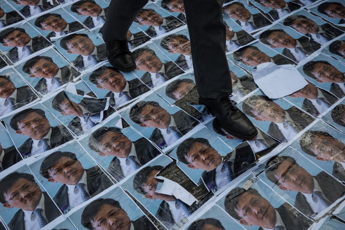 A student walks over posters of pro-China lawmaker Junius Ho during a protest outside the Queen Elizabeth Stadium where Hong Kong leader Carrie Lam held her first community dialogue on Sept. 26 in Hong Kong.