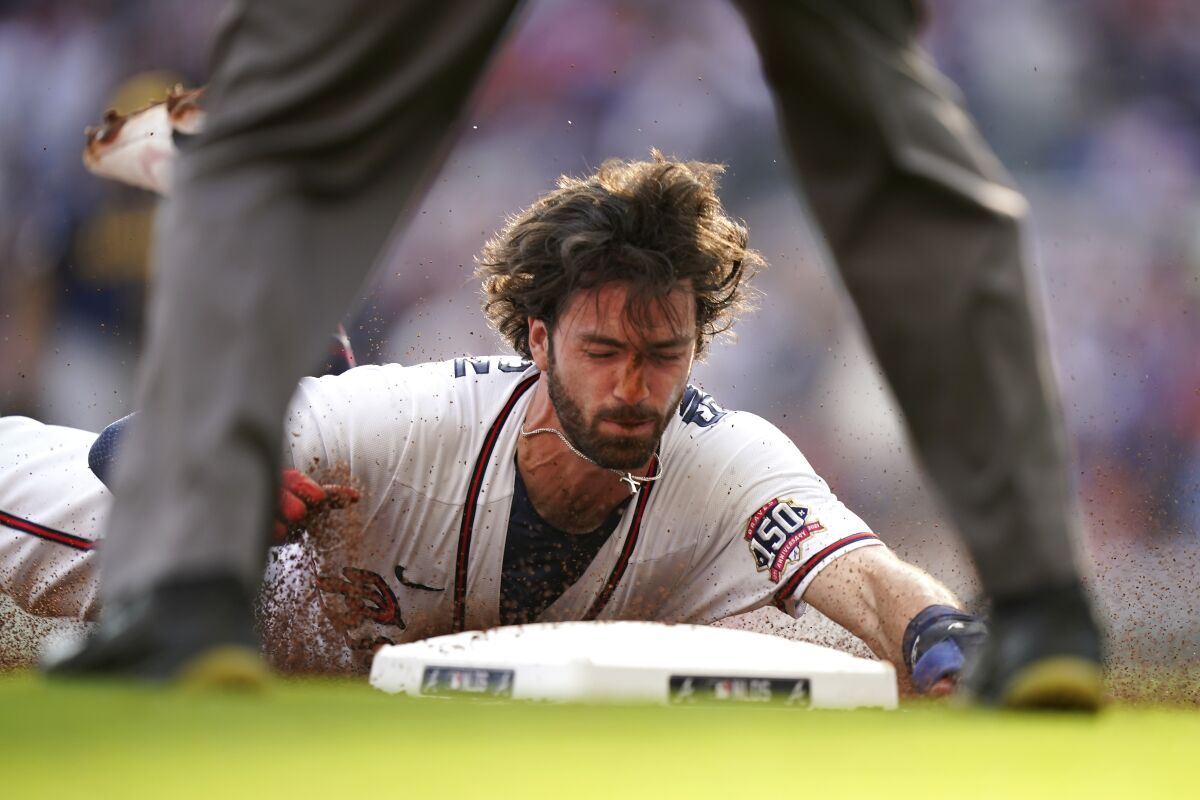 Atlanta Braves' Dansby Swanson (7) slides into third base during the first inning of Game 4 