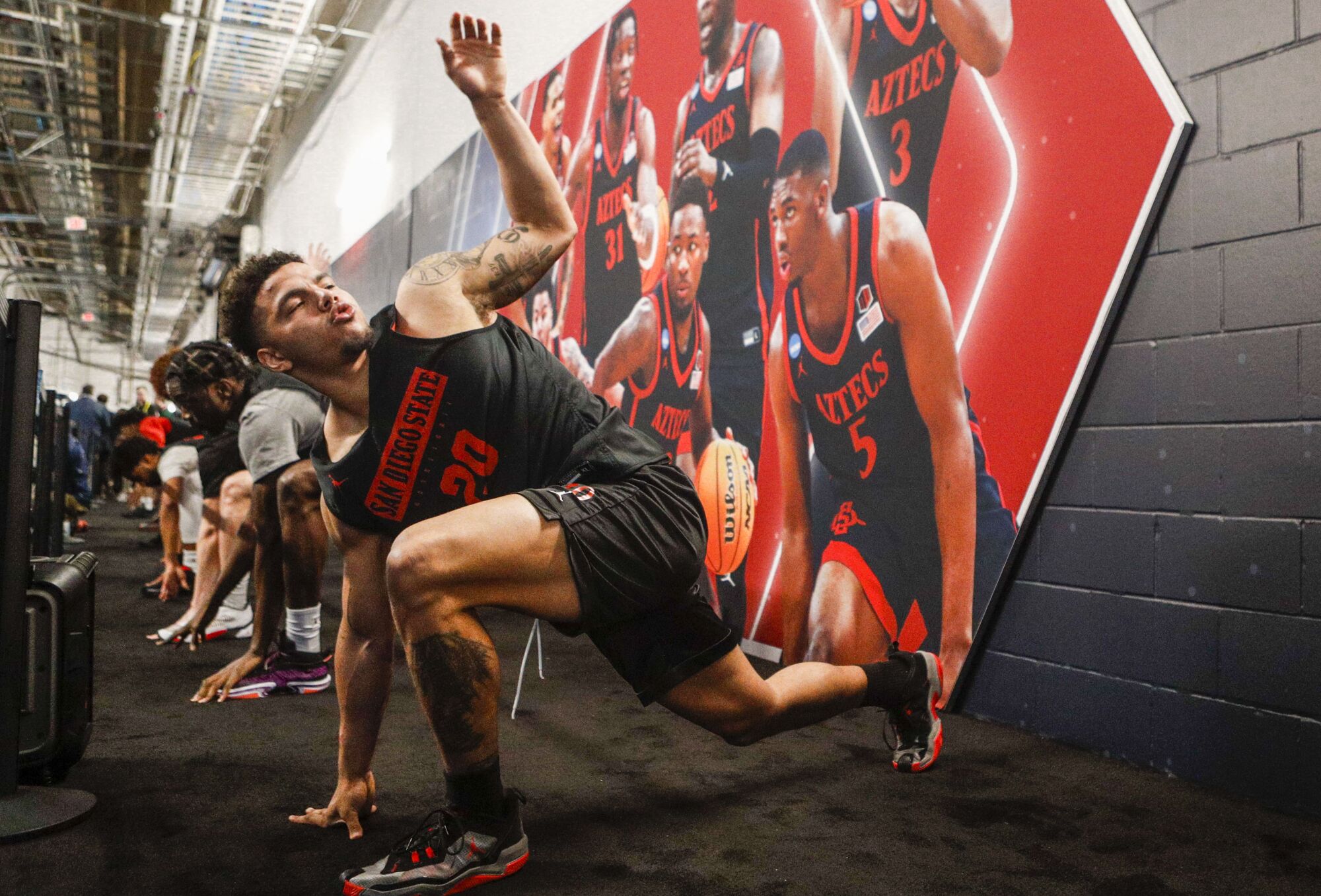 San Diego State guard Matt Bradley (20) and teammates stretch near a mural composed of 