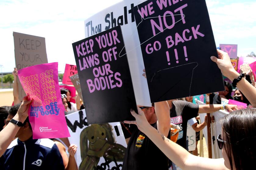 An anti-abortion protester is surrounded by those attending the Planned Parenthood's national day of action "Bans Off Abortion" rally at Centennial Regional Park in Santa Ana on Saturday, May 14, 2022. Hundreds listened to inspirational speakers, including local politicians like 45th district Congresswoman Katie Porter, for about 2 hours.