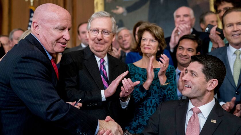 House Speaker Paul D. Ryan (R-Wis.), right, shakes hands with House Ways and Means Committee Chairman Kevin Brady (R-Texas) as GOP leaders celebrate passage of their tax-cut bill.