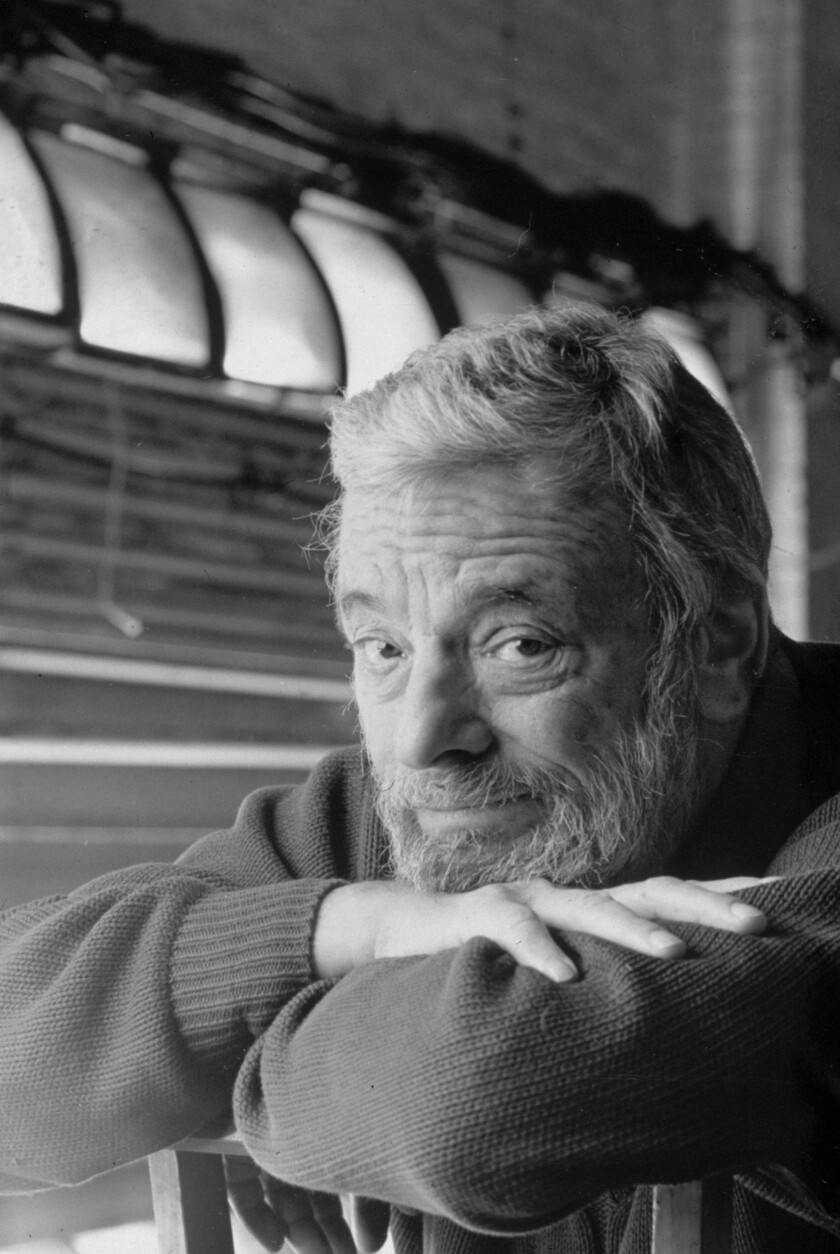 American composer and lyricist Stephen Sondheim leans his arms on the back of a chair.