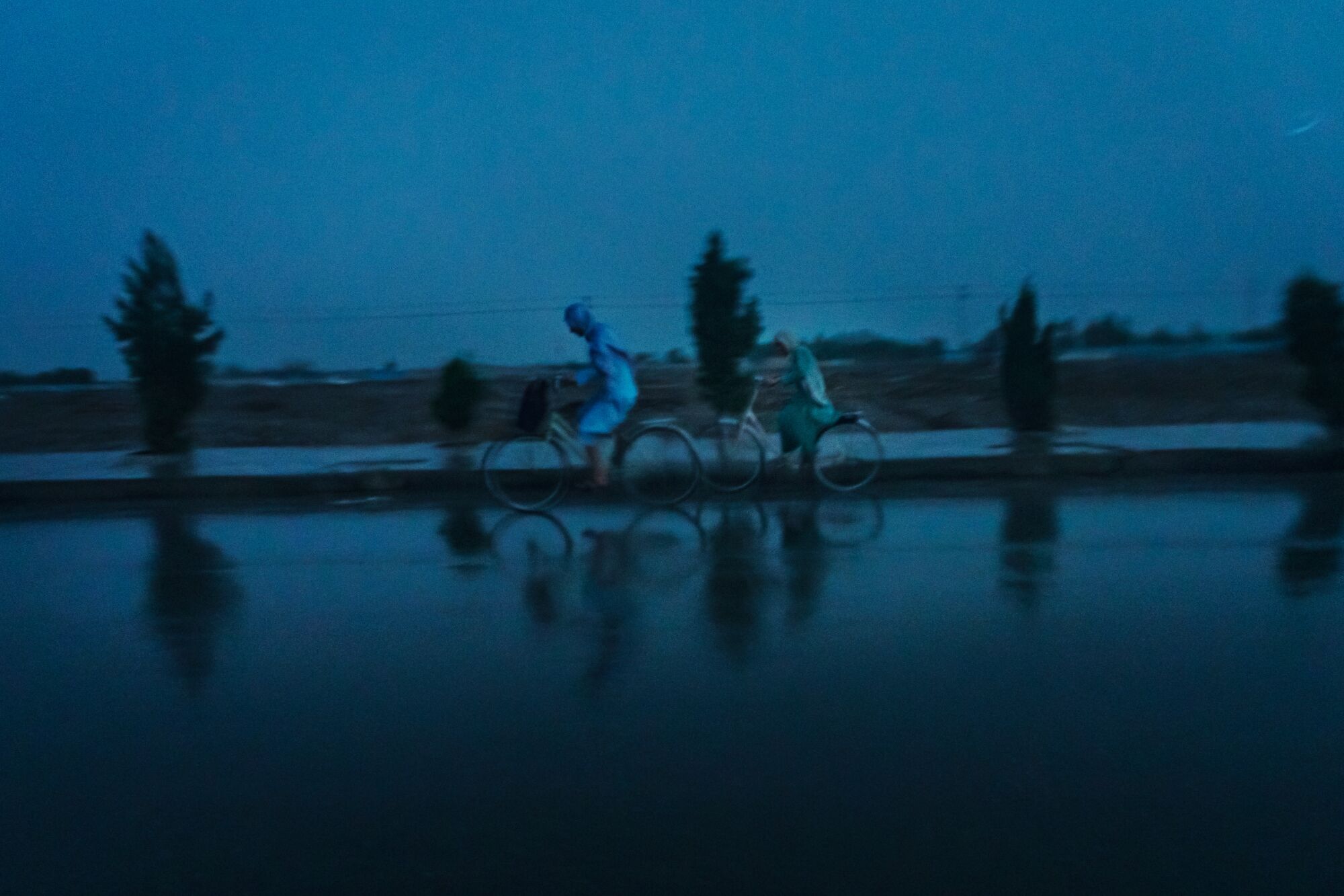 Cyclists pedal through a downpour in Kandahar, Afghanistan on May 3, 2021. 
