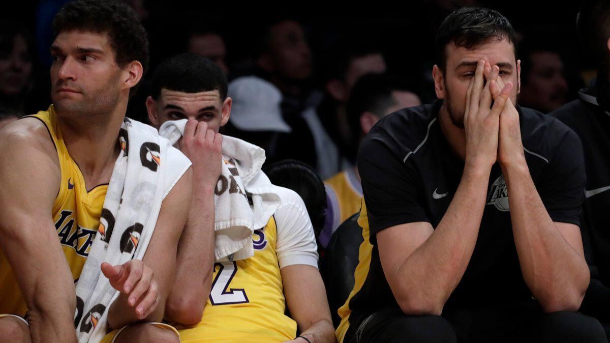 Lakers center Andrew Bogut, right, sits on the bench with teammates Lonzo Ball, center, and Brook Lopez during a loss to the Charlotte Hornets at Staples Center on Friday.