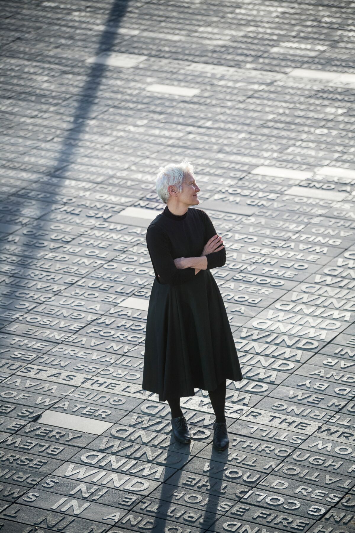 A woman in black clothes stands on a walkway engraved with words.