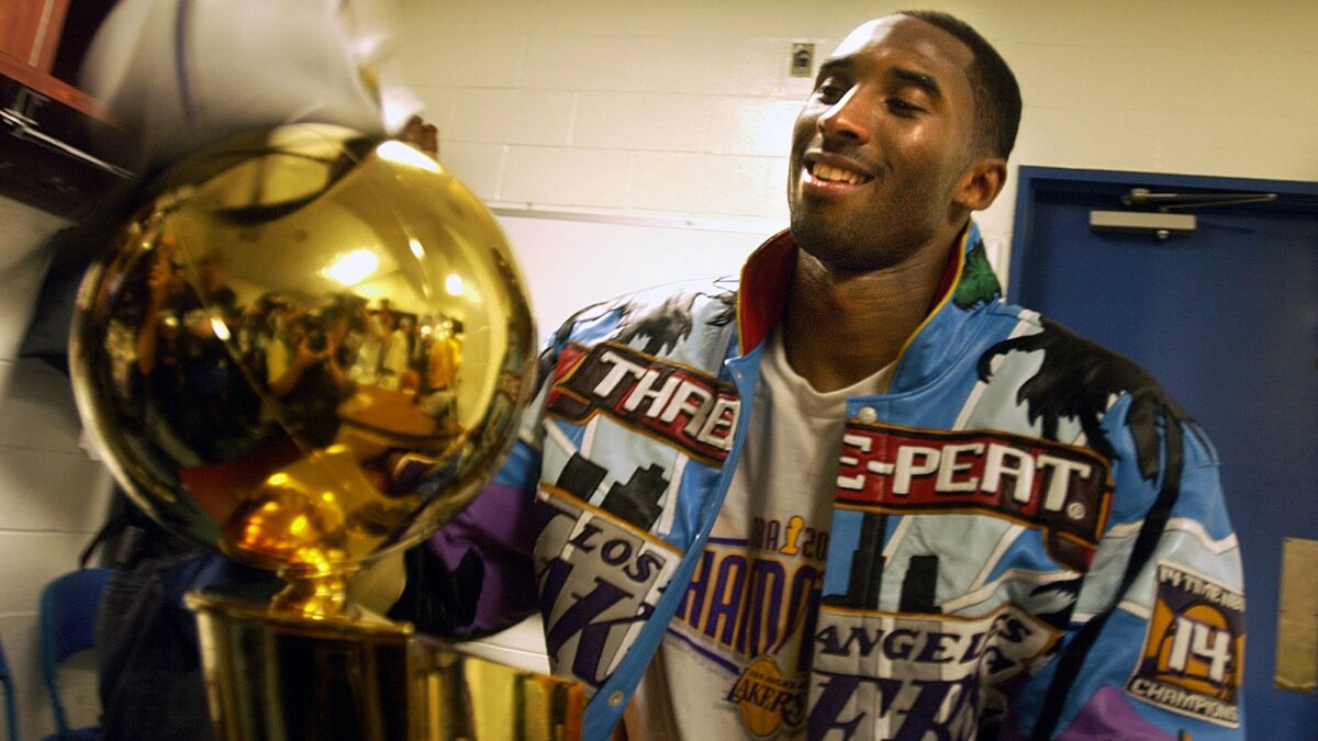 Kobe Bryant looks at the Larry O'Brien trophy after the Lakers' NBA championship victory over New Jersey on June 12, 2002.