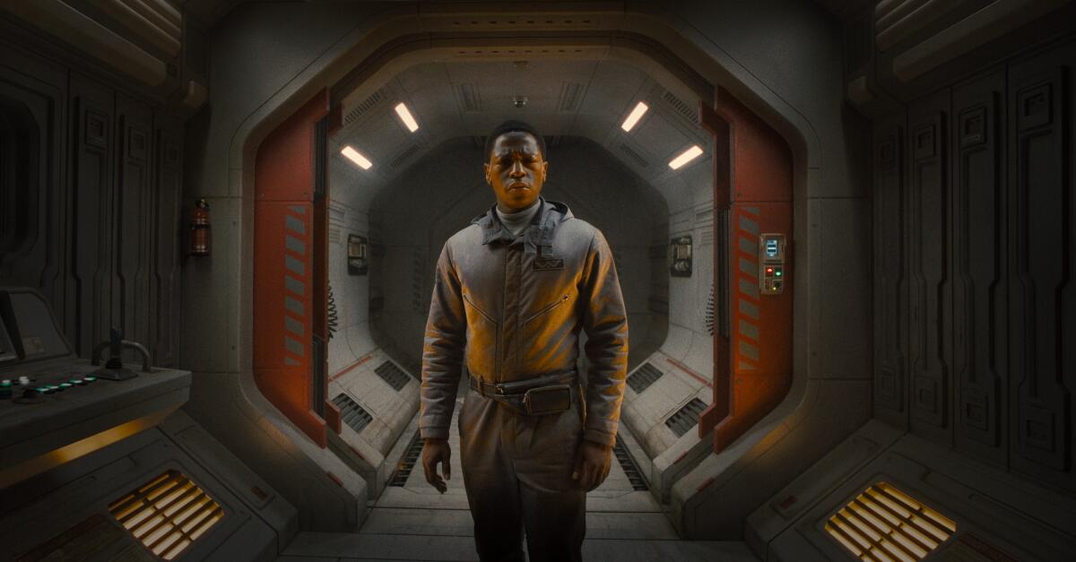 A man stands in the hallway of a spaceship.