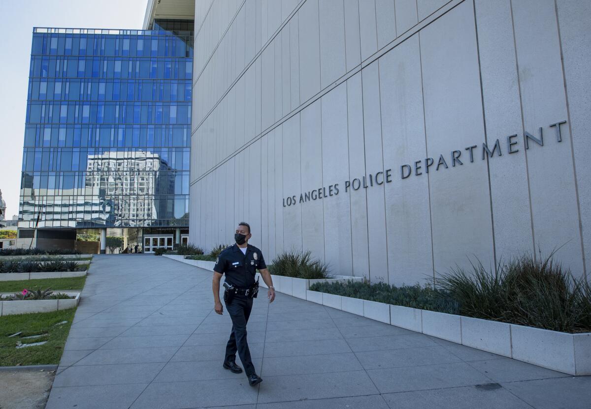 A uniformed LAPD officer wearing a facial mask walks outside department headquarters in downtown L.A. 