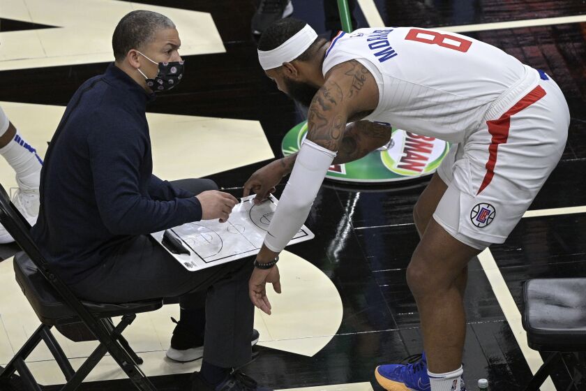 Los Angeles Clippers head coach Tyronn Lue, left, and forward Marcus Morris Sr. (8) discuss a play during a timeout in the second half of an NBA basketball game against the Orlando Magic, Friday, Jan. 29, 2021, in Orlando, Fla. (AP Photo/Phelan M. Ebenhack)