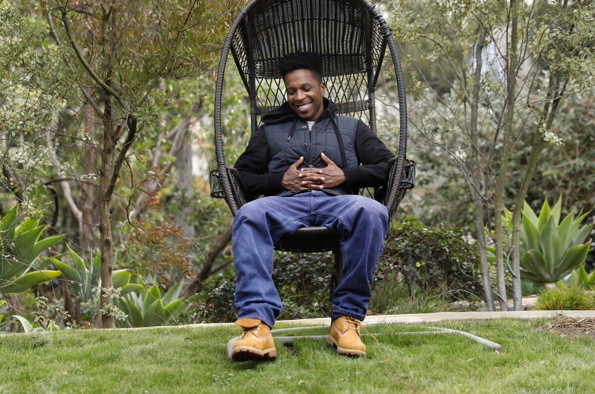 Actor Leslie Odom Jr sits in a hanging chair in his backyard