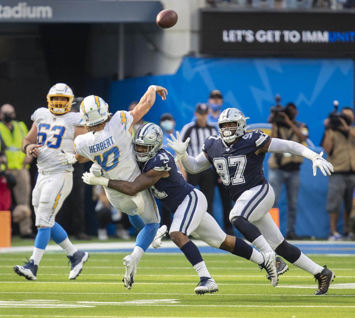 Chargers quarterback Justin Herbert throws to avoid being sacked by Dallas Cowboys linebacker Micah Parsons.