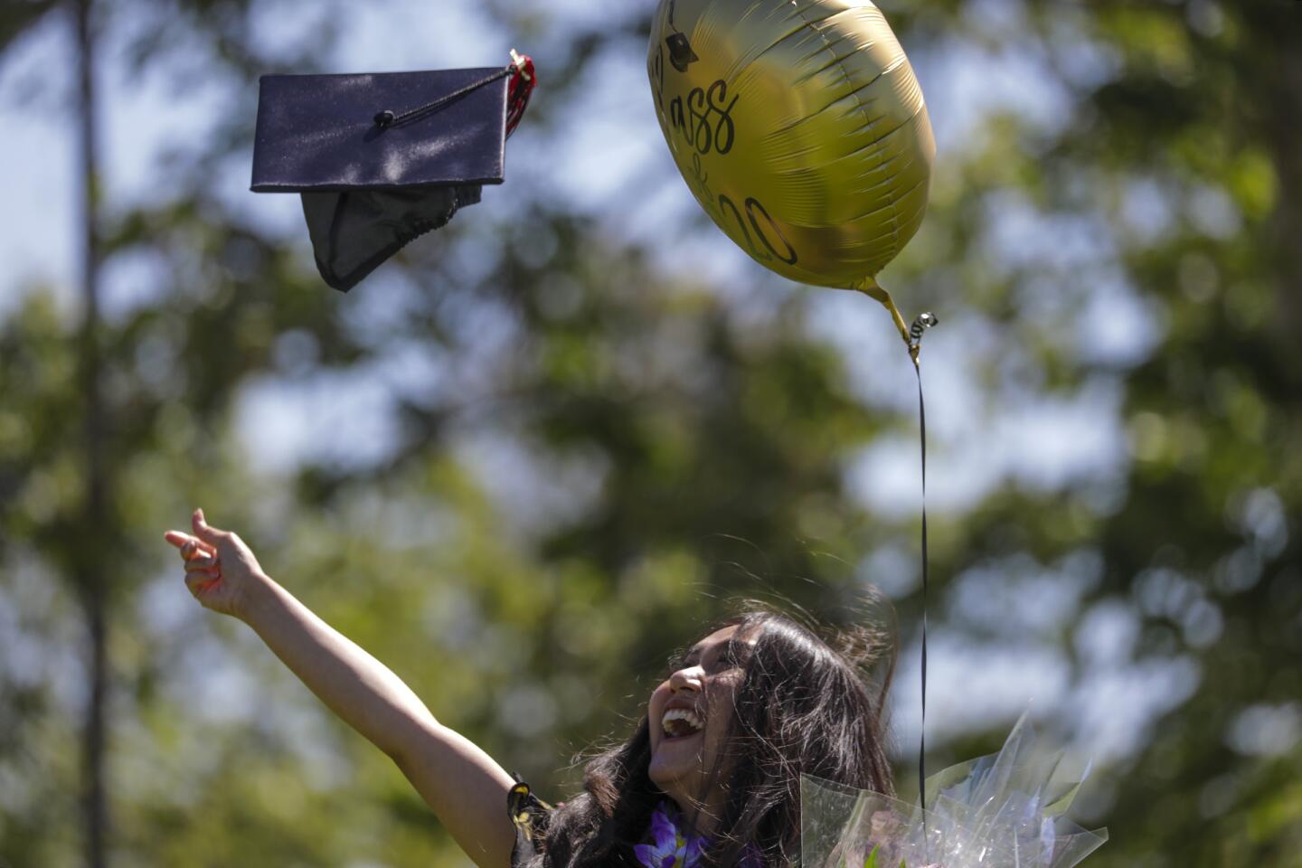 Graduate Sarah Anggraini throws her cap in the air for a family photo.