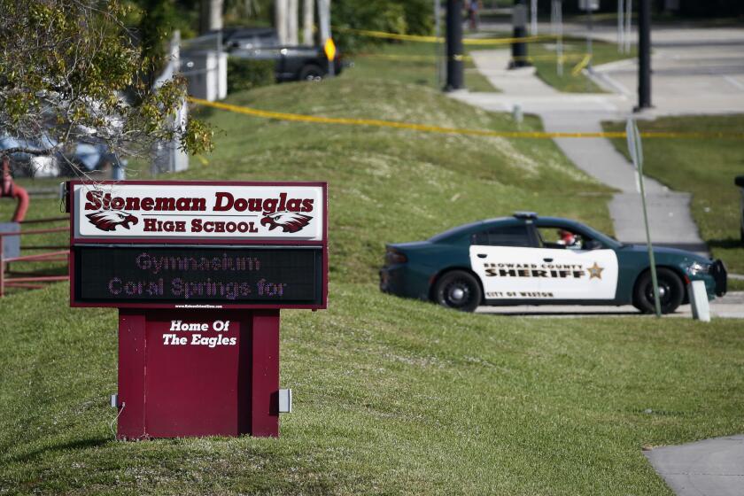 FILE- In this Feb. 15, 2018, file photo, law enforcement officers block off the entrance to Marjory Stoneman Douglas High School in Parkland, Fla., following a deadly shooting at the school. A California man who is on the autism spectrum was sentenced Monday, March 2, 2020, to more than five years in prison for cyberstalking families of Parkland, Florida, school shooting victims. (AP Photo/Wilfredo Lee, File)