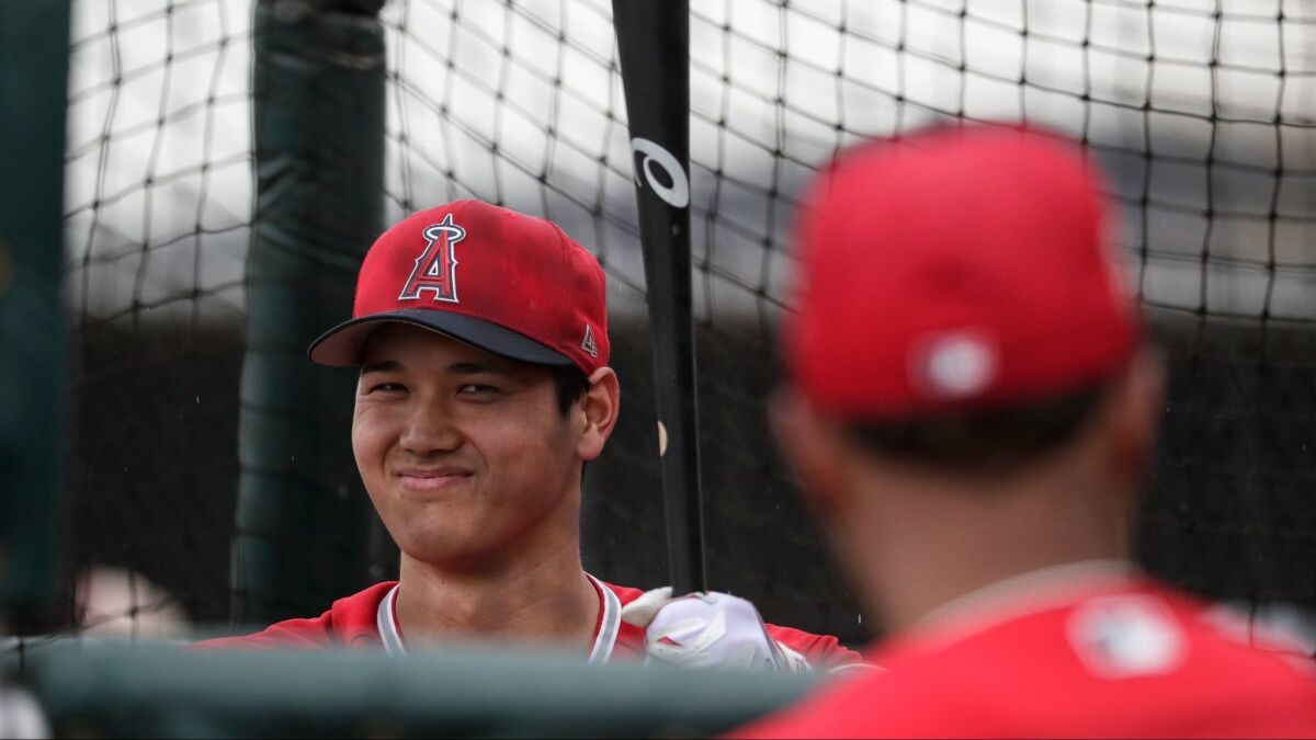 Shohei Ohtani is closely watched by teammates at batting practice during first day of spring training.